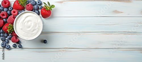 Flat lay image of a light blue wooden table adorned with delicious cream cheese and fresh berries providing ample room for text