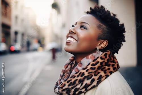 young african american woman wearing a leopard print scarf in the street looking up with a smile