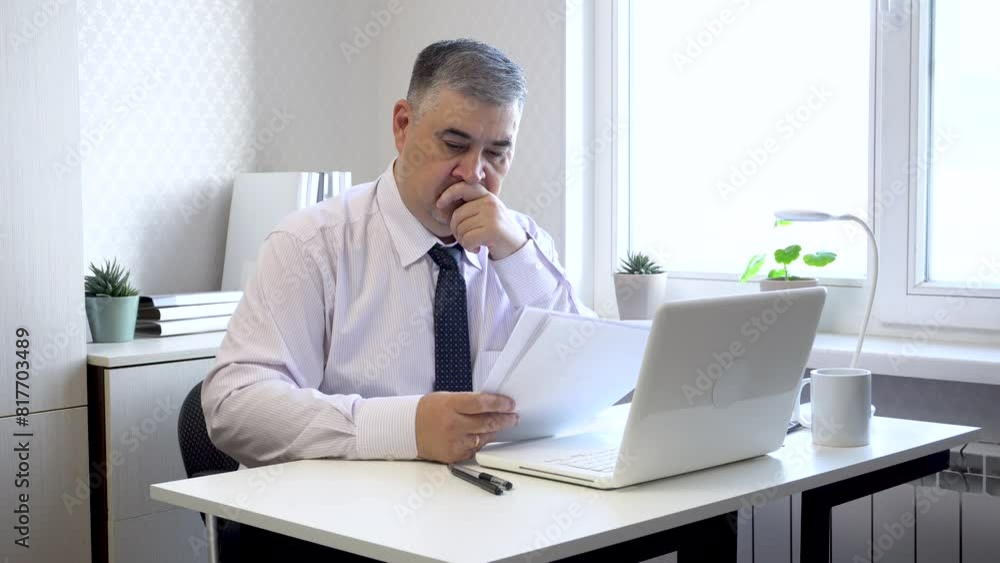 A man in a tie works at a computer, then thinks and looks out the window. The video is suitable for content about working in the office, running a business, or remote work. A man in a tie works at a computer, then thinks and looks out the window. The video is suitable for content about working in the office, running a business, or remote work.