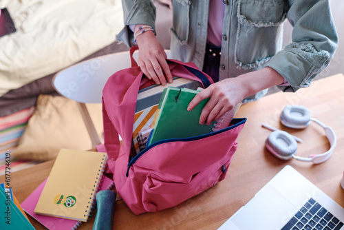 High angle view of unrecognizable student getting ready for school packing her backpack, copy space