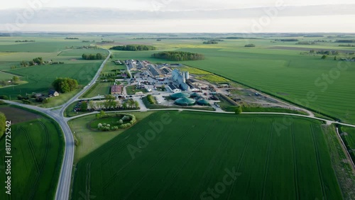 Areial view with wide agricultural fields with highway and dirt road infrastructure. In the distance, an agricultural production complex with a biogas plant, a pig farm and grain storage containers.