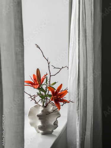 Creative floral arrangement in a ceramic vase on the windowsill in the living room
