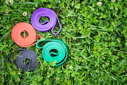 set of colorful elastic fitness bands  on green grass. Outdoor workouts concept . Copy space , close up view