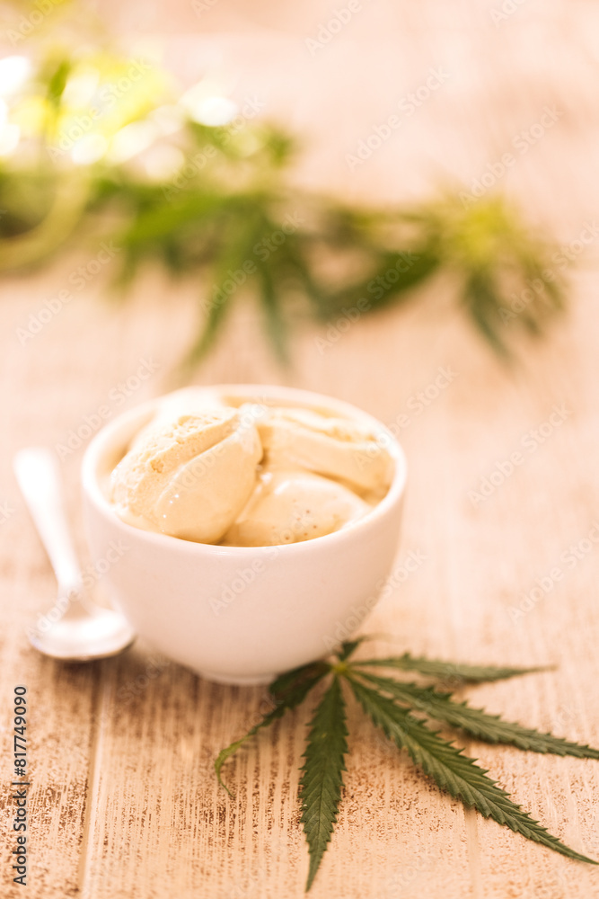 A hemp leaf is lying on a mock-up jars of ice cream on a table A hemp leaf is lying on a mock-up jars of ice cream on a table