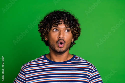 Photo of impressed afraid scared man wear trendy striped clothes look empty space isolated on green color background