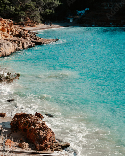 Scenic view of Ibiza beach with fishermen's huts, blue water and rocks on Beach Cala Saladeta photo