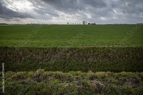Dutch landscape with ditch in foreground under heavy skies