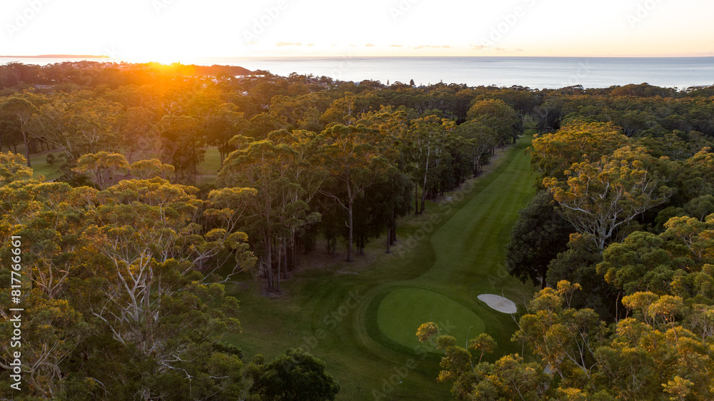 Obraz premium a bird's eye view of a golf course with the sun rising over trees