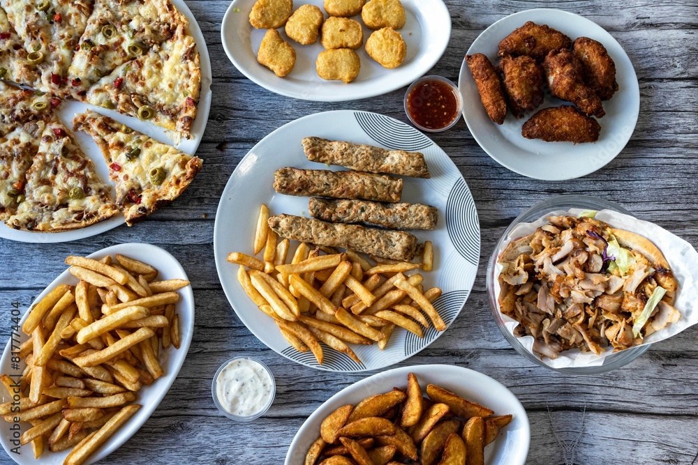 Close-up of an assortment of prepared dishes with pizza and French fries on a wooden table Close-up of an assortment of prepared dishes with pizza and French fries on a wooden table