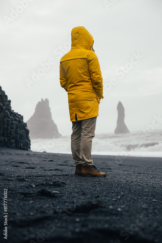 Wanderlust explorer discovering icelandic natural wonders. Man spending time on the black sand beach watching the big waves.