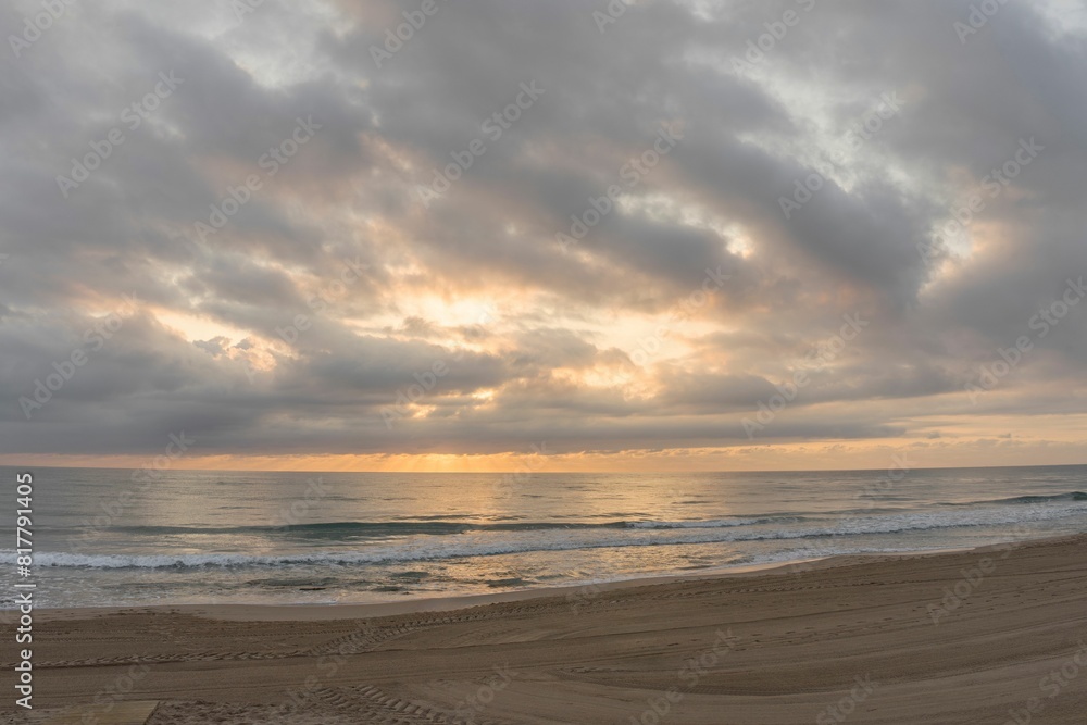 Close-up of Gandia beach at sunrise with some clouds in the golden sky. Panoramic beach landscape. Close-up of Gandia beach at sunrise with some clouds in the golden sky. Panoramic beach landscape.