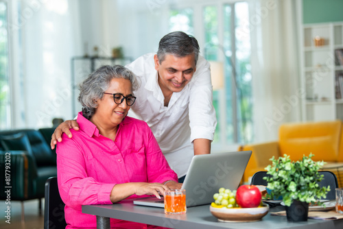 senior Indian asian mid age couple having fun during a breakfast at home using laptop computer.