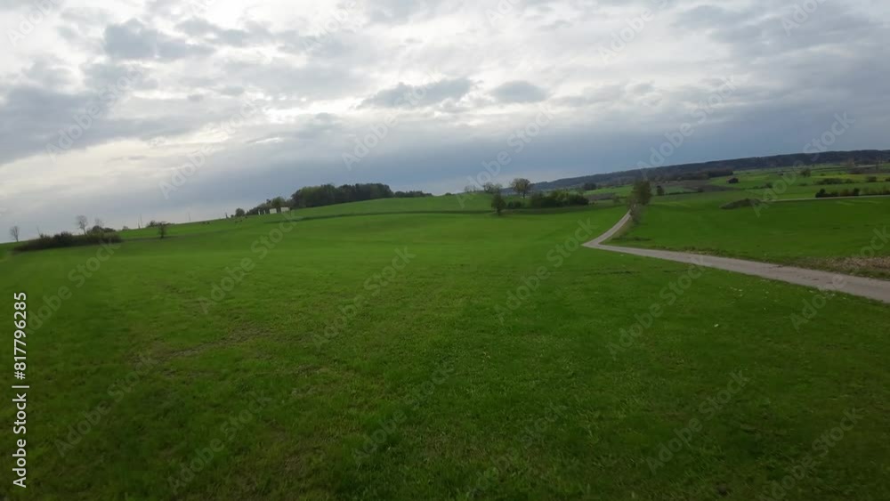Drone shot of the trails passing through green fields with a small rural village in the background Drone shot of the trails passing through green fields with a small rural village in the background