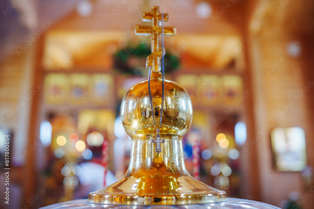 Φωτογραφία A cross on a chain hangs on a large cross on the lid of the baptismal font in the church