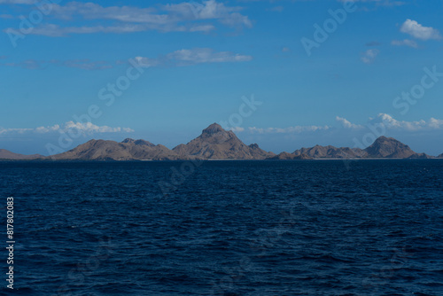 Serene view of a rocky island rising from the blue ocean under a clear sky.