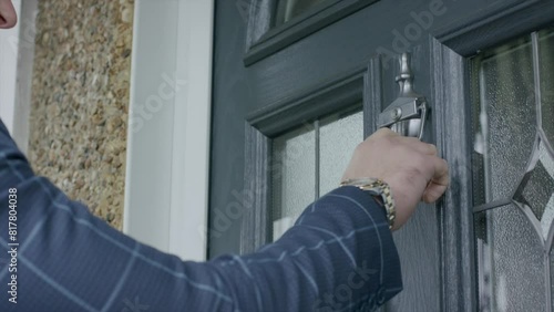 Closeup footage of adult male hand using the door knocker to knock the door