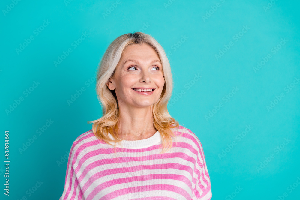 Portrait of charming senior person with wavy hairdo wear striped pullover look at sale empty space isolated on blue color background Portrait of charming senior person with wavy hairdo wear striped pullover look at sale empty space isolated on blue color background