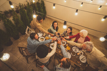 Storytelling image of a multiethnic group of people dining on a rooftop. Family and friends make a reunion at home ad dining outdoor.