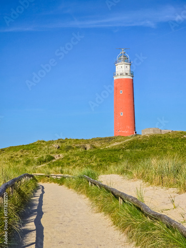 A vibrant red lighthouse stands proudly atop a lush green hill on the island of Texel  Netherlands.