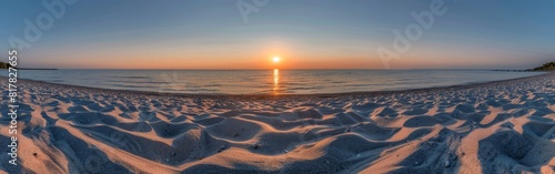 The sun is setting low in the sky  casting a warm glow over the water at the beach with white sand