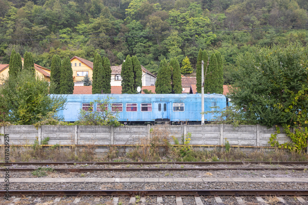 Blue train parked in a residential area, along a set of railroad tracks Blue train parked in a residential area, along a set of railroad tracks