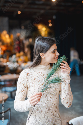 A young woman learning to make a holiday wreath at a decoration workshop.