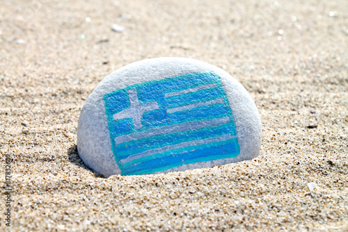 Greece country flag painted on the sea stone on empty sandy beach close up. Vacation concept.