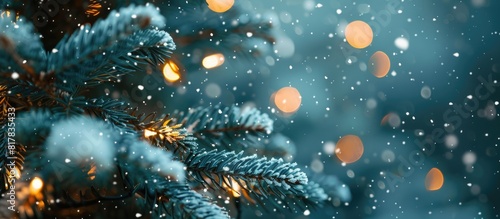 Christmas tree covered in snow with twinkling lights in the background