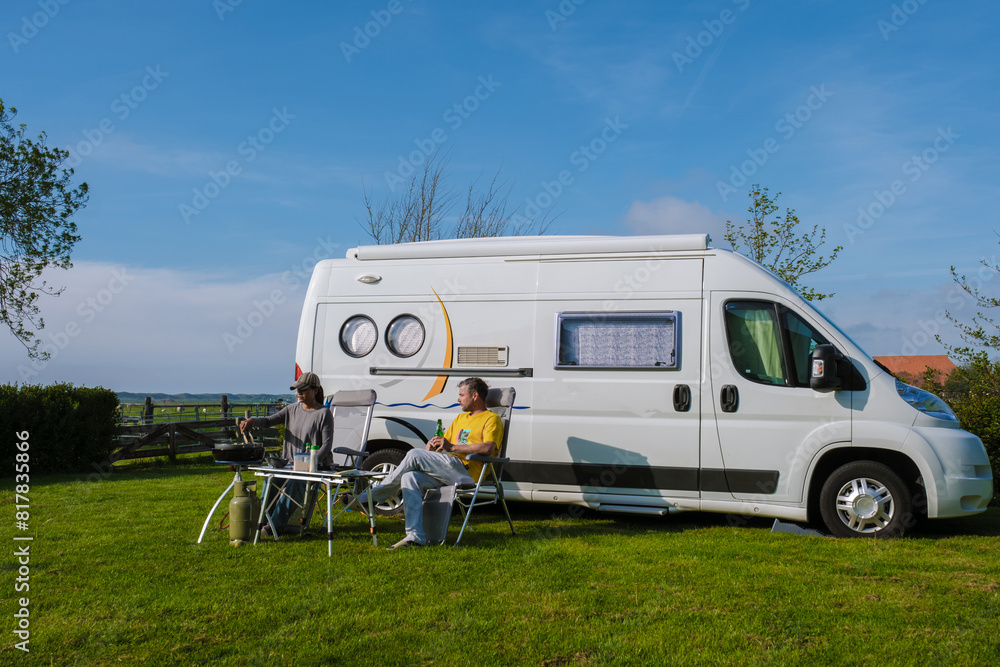 Two individuals enjoying a scenic moment of relaxation outside their camper van in Texel, Netherlands. a couple on a camping trip, camping at a farm in Texel Netherlands