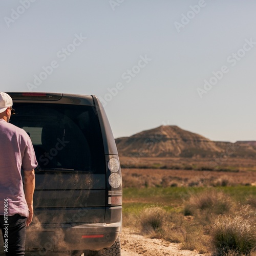 a man looking out into a barren landscape near his van © Wirestock