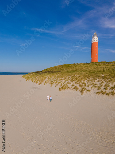 A majestic lighthouse stands tall on a sandy beach, guiding ships safely to shore with its bright beacon of light against the backdrop of the sea.