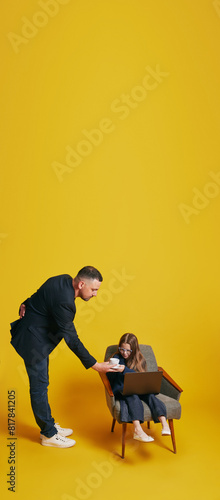 Father-Daughter Work Session. Father and daughter in formal attire working together. Dad helps daughter against sunny-yellow background. Concept of Father s day. Children s day  Family day  parenthood