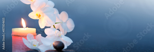 Spa background with white orchid , candle and zen black stones on gray.