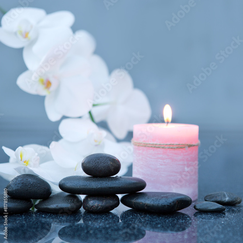 Spa background with white orchid   candle and zen black stones on gray.