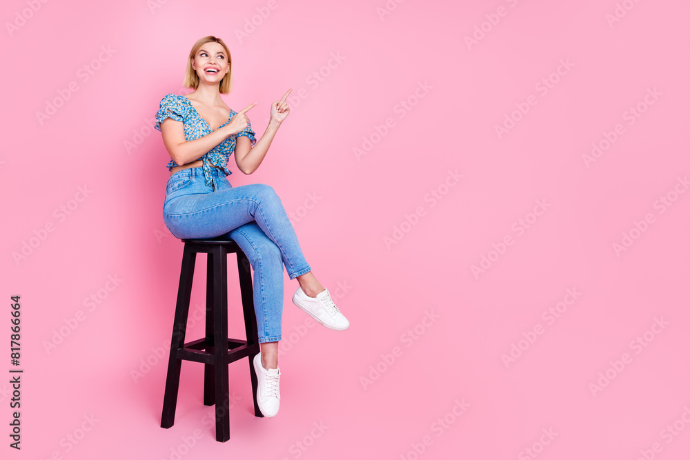 Full body portrait of nice young lady look point fingers empty space sit stool wear top isolated on pink color background Full body portrait of nice young lady look point fingers empty space sit stool wear top isolated on pink color background