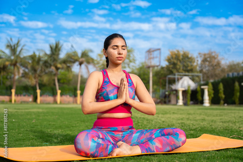 Fit young indian woman practicing surya namaskar yoga pose in garden. exercise, workout, meditation, well being, mental health concept.