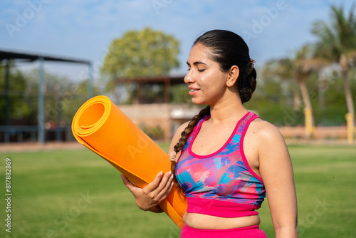 Sporty young indian girl with yoga mat. exercise, meditation for workout, mental health, garden, outdoor, healthy lifestyle.
