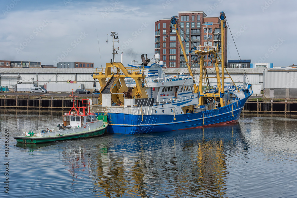 blue and white painted stern trawler sails across the canal