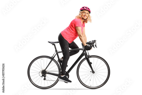 Happy middle aged woman in sportswear riding a bicycle with a helmet