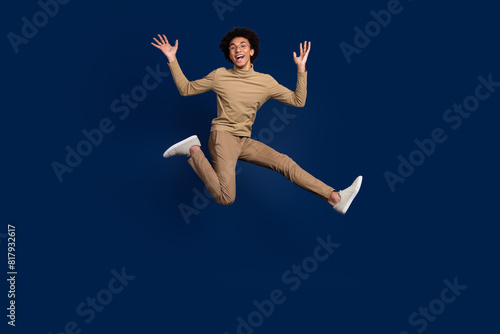 Full body photo of attractive young man jump running excited dressed stylish beige clothes isolated on dark blue color background