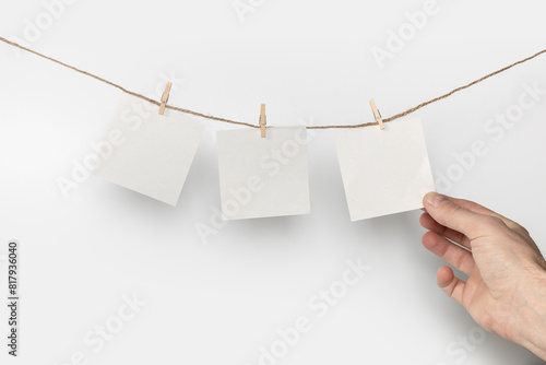 man hand take paper note cards hanging with wooden clip or clothespin on rope string peg on white background photo