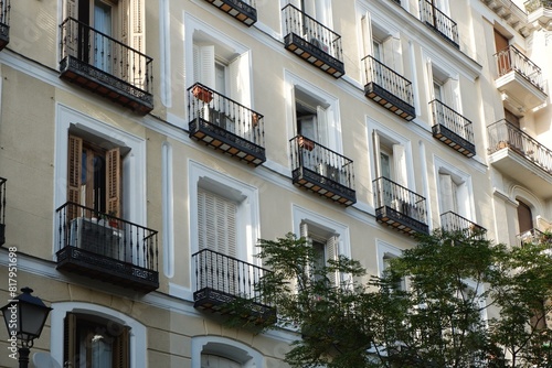 Classical facade of light colour with shuttered windows and tiny balconies downtown Madrid, Spain. Vintage spanish architecture