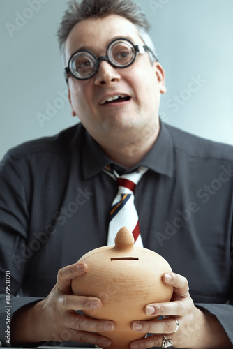 Spiky-haired man, glasses, holds piggy bank photo