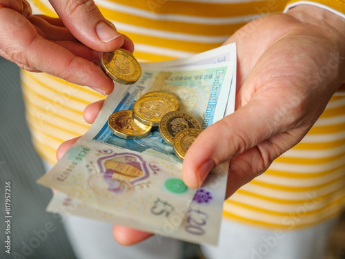 Close up of hands paying out cash money in UK pounds banknotes and coins photo