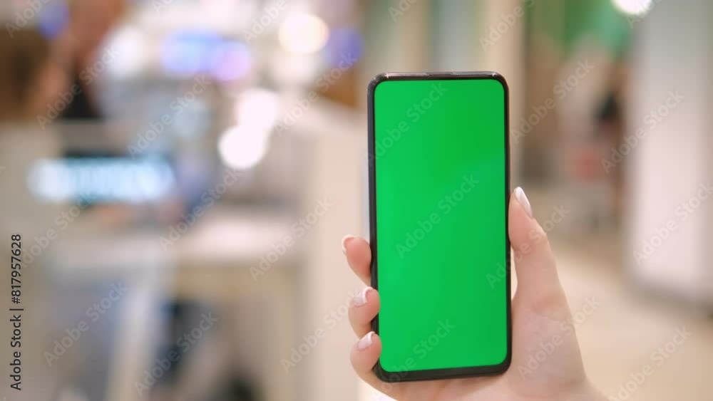 Mall. Shopping center. Back view of brunette holding chroma key green screen smartphone watching content. Shopping online. Gadgets and contemporary people concept. 4K Mall. Shopping center. Back view of brunette holding chroma key green screen smartphone watching content. Shopping online. Gadgets and contemporary people concept. 4K