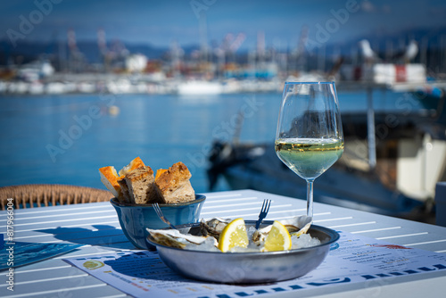 Fototapeta Naklejka Na Ścianę i Meble -  Piatto di ostriche e calice di vino bianco nel porto turistico di La Spezia, Liguria, Italia