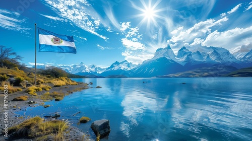 The flag of Argentina waves above a tranquil lake with mountains in the background photo