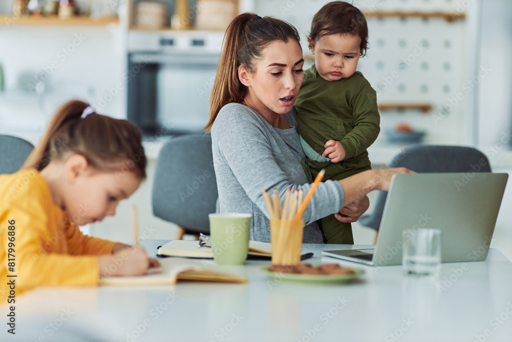 A busy mother waking care of her children while also working from home A busy mother waking care of her children while also working from home