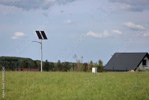 Panel słoneczny, turbina wiatrowa na latarni ulicznej, wieś w górach.
