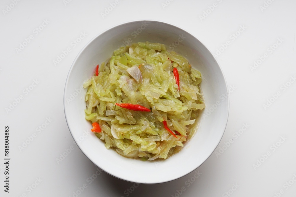 Stir-fried chayote vegetables with chopped garlic and red chilies in a white bowl on a white background Stir-fried chayote vegetables with chopped garlic and red chilies in a white bowl on a white background